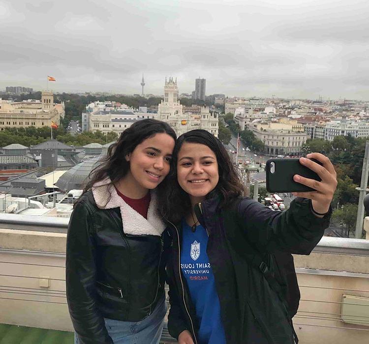 two girls take a selfie in Madrid overlooking church in distance